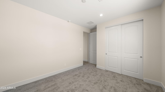 unfurnished bedroom featuring a closet and light carpet