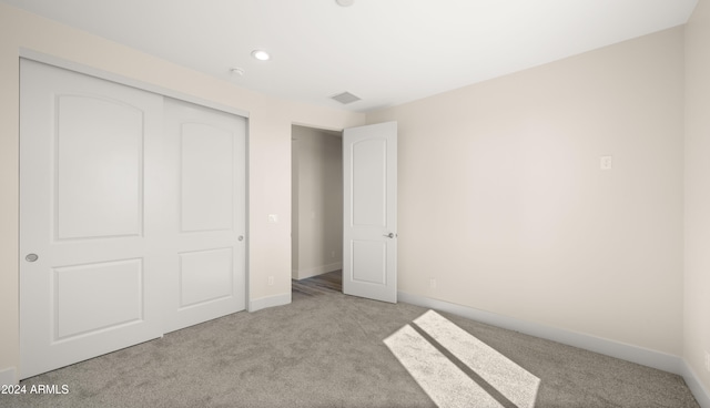 unfurnished bedroom with a closet and light carpet