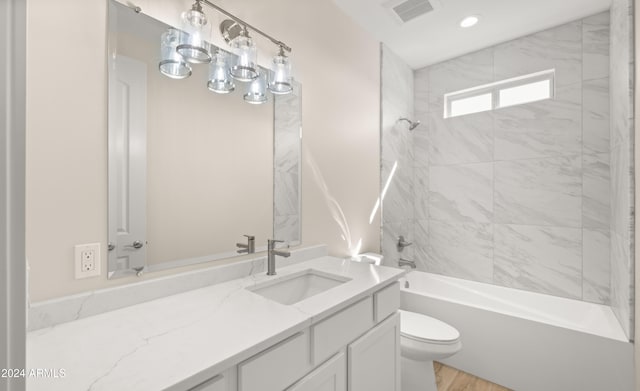 full bathroom with toilet, tiled shower / bath combo, vanity, and hardwood / wood-style floors