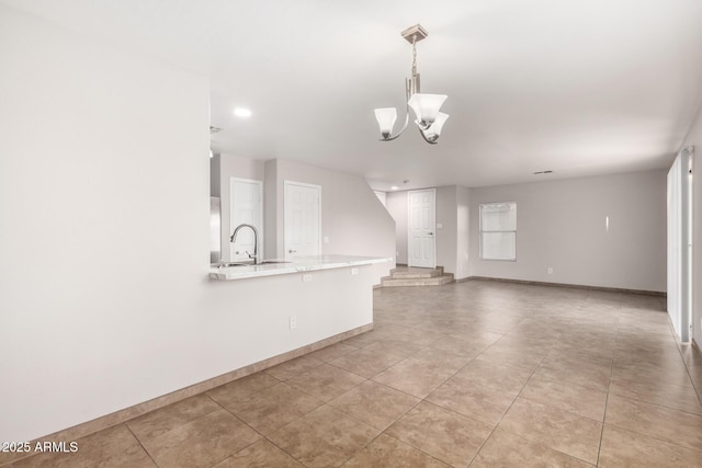 unfurnished living room featuring an inviting chandelier, sink, and light tile patterned floors