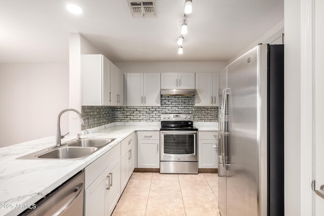 kitchen featuring sink, light tile patterned floors, appliances with stainless steel finishes, white cabinetry, and tasteful backsplash