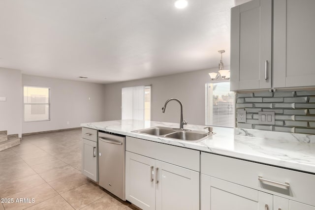 kitchen with light stone counters, stainless steel dishwasher, sink, and hanging light fixtures