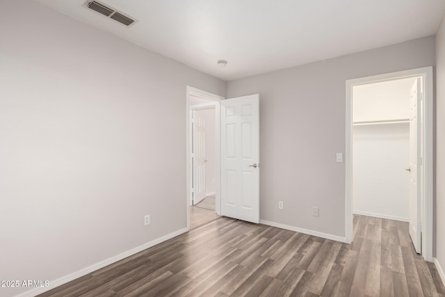 unfurnished bedroom featuring hardwood / wood-style flooring, a walk in closet, and a closet