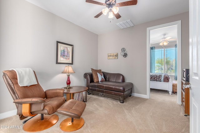 living area with ceiling fan and light colored carpet