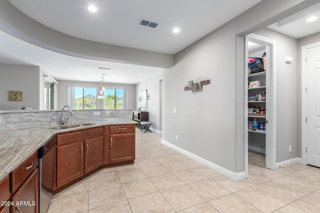 kitchen with pendant lighting, dishwasher, sink, and light stone counters