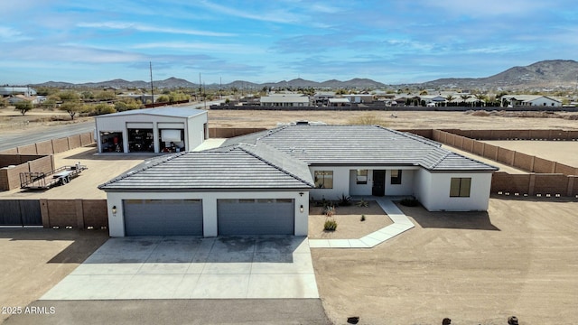 single story home with concrete driveway, fence, a mountain view, and stucco siding