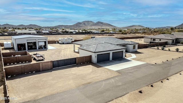 view of front of house with driveway, a tiled roof, an attached garage, fence private yard, and a mountain view