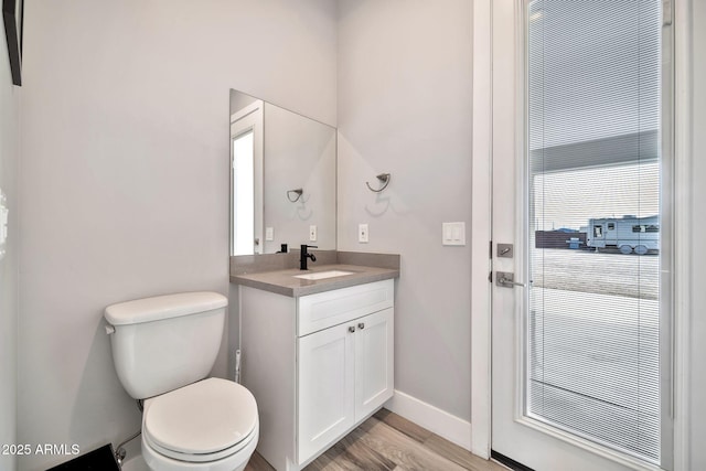 bathroom with baseboards, vanity, toilet, and wood finished floors