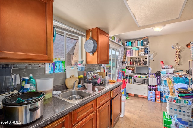 kitchen featuring sink, tasteful backsplash, light tile floors, and a textured ceiling