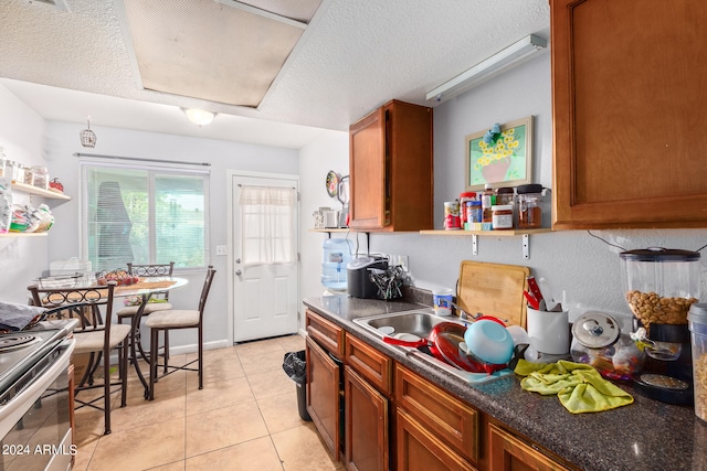 kitchen with a textured ceiling, gas range, and light tile floors