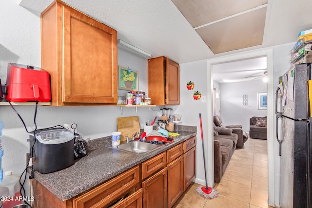 kitchen featuring ceiling fan, sink, light tile flooring, and refrigerator