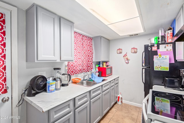 kitchen featuring black fridge, range, light tile floors, gray cabinetry, and sink