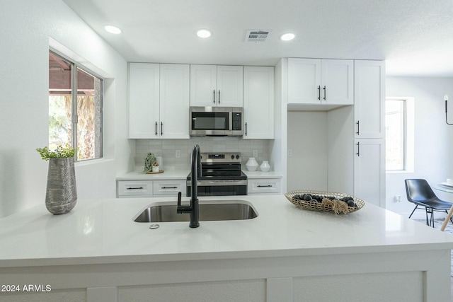 kitchen featuring decorative backsplash, appliances with stainless steel finishes, and white cabinetry