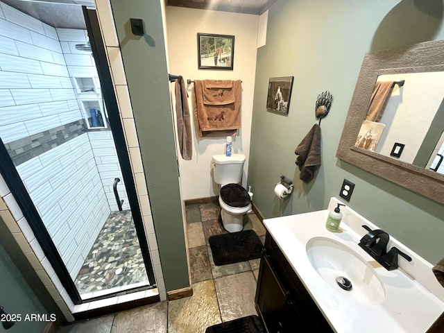 bathroom featuring a tile shower, vanity, and toilet