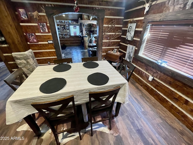 dining space with dark wood-type flooring and wooden walls