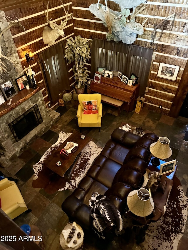 interior space featuring a stone fireplace, vaulted ceiling, and wooden walls