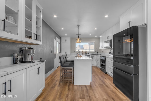 kitchen with a center island, appliances with stainless steel finishes, white cabinets, and light hardwood / wood-style floors