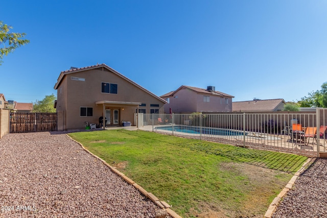 rear view of house with a lawn, a fenced in pool, and a patio area