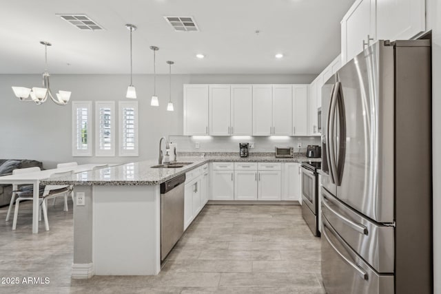 kitchen featuring pendant lighting, sink, appliances with stainless steel finishes, white cabinetry, and light stone countertops