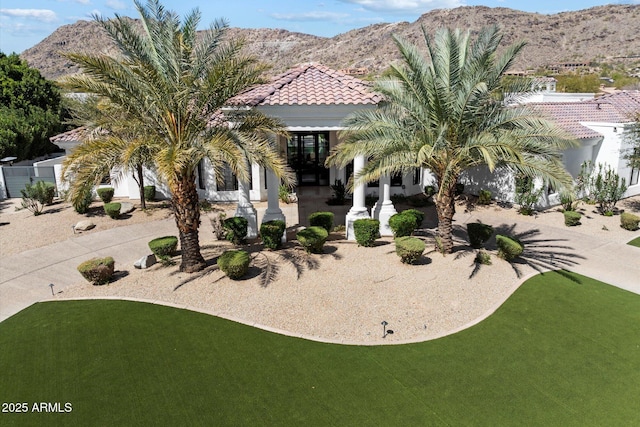 view of front facade featuring a patio, fence, stucco siding, a tile roof, and a mountain view