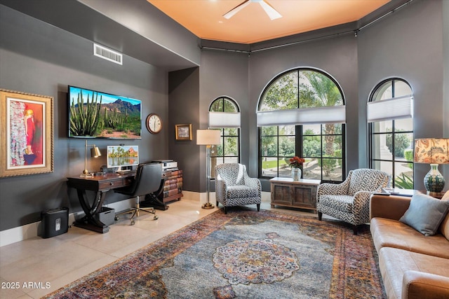 office featuring tile patterned flooring, visible vents, baseboards, and a towering ceiling