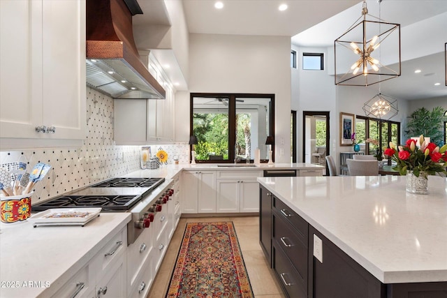 kitchen featuring a notable chandelier, a sink, white cabinets, custom exhaust hood, and stainless steel gas cooktop