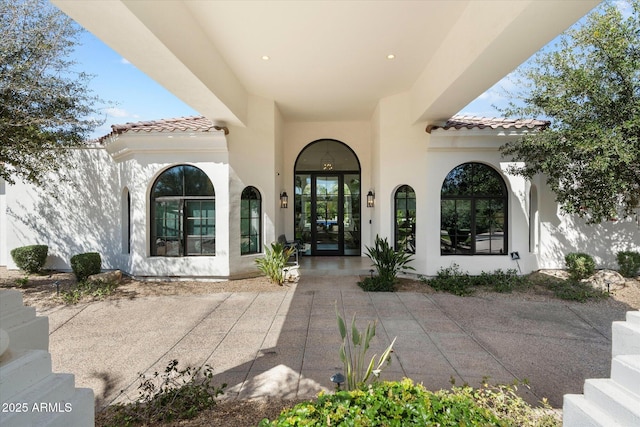 view of exterior entry featuring stucco siding and a tiled roof