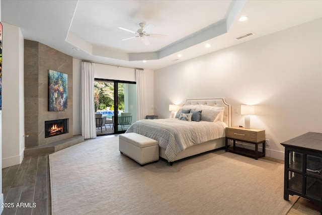 bedroom with visible vents, access to outside, baseboards, a raised ceiling, and a tile fireplace