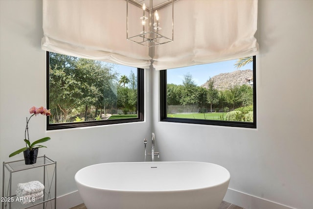 full bath featuring a notable chandelier, baseboards, and a soaking tub