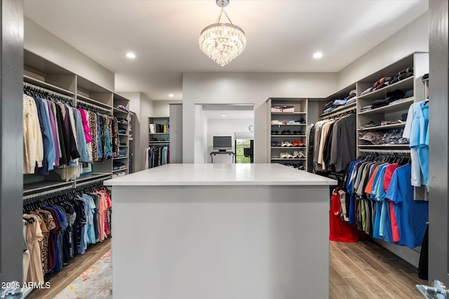 spacious closet with a chandelier and wood finished floors