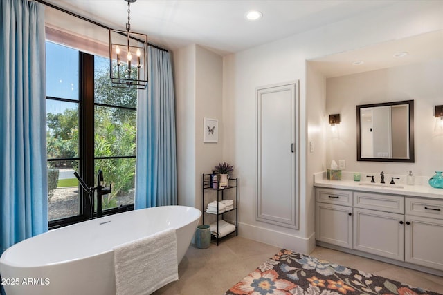 full bath with vanity, an inviting chandelier, recessed lighting, a freestanding bath, and tile patterned flooring