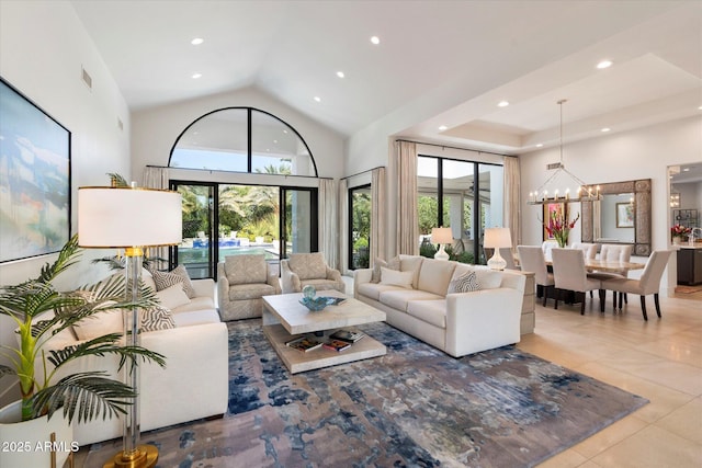 living area with a notable chandelier, visible vents, a wealth of natural light, and high vaulted ceiling