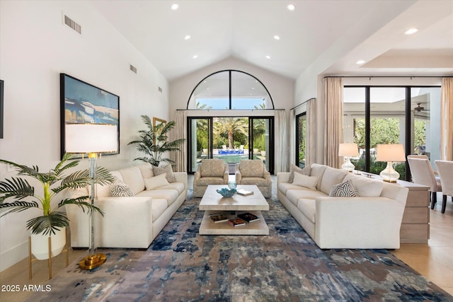 living area with a wealth of natural light, visible vents, high vaulted ceiling, and recessed lighting