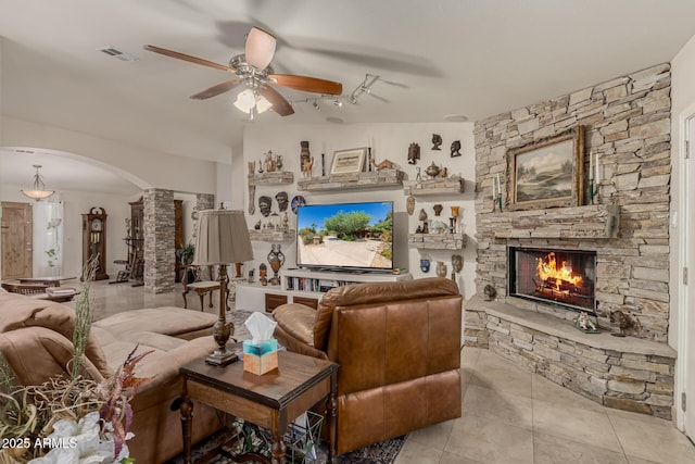 12837 N 68th St, Scottsdale, AZ 85254 - tiled living area with arched walkways, ceiling fan, a stone fireplace, and vaulted ceiling