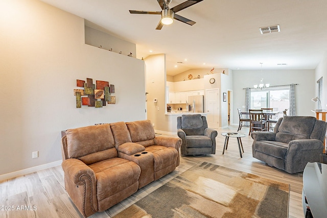 living room featuring ceiling fan with notable chandelier, lofted ceiling, and light hardwood / wood-style flooring