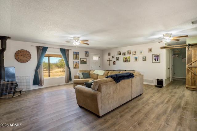 8730 E Barataria Blvd, Sierra Vista, AZ 85650 - living room with a barn door, a ceiling fan, wood finished floors, a textured ceiling, and a wood stove