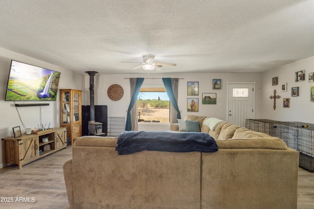 8730 E Barataria Blvd, Sierra Vista, AZ 85650 - living room with light wood-style flooring, a ceiling fan, healthy amount of natural light, a wood stove, and a textured ceiling