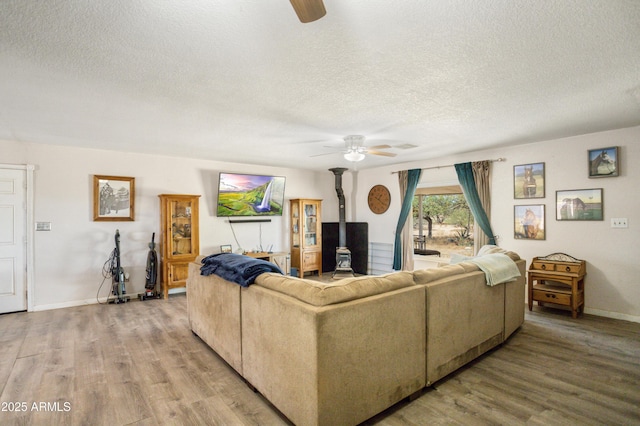 8730 E Barataria Blvd, Sierra Vista, AZ 85650 - living room with ceiling fan, a textured ceiling, wood finished floors, a wood stove, and baseboards