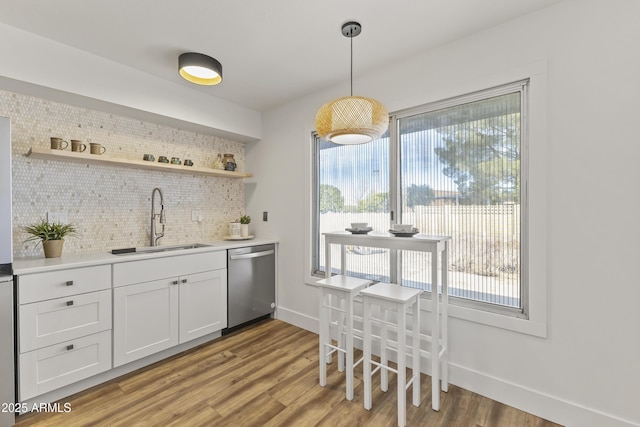 bar featuring decorative light fixtures, sink, white cabinets, decorative backsplash, and stainless steel dishwasher