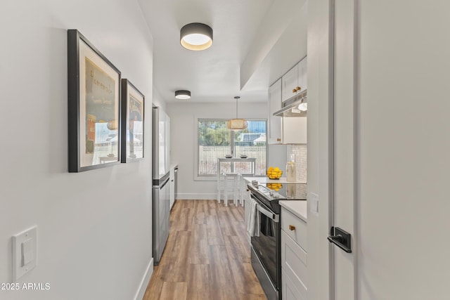 kitchen featuring white cabinetry, hardwood / wood-style floors, stainless steel range with electric stovetop, tasteful backsplash, and decorative light fixtures