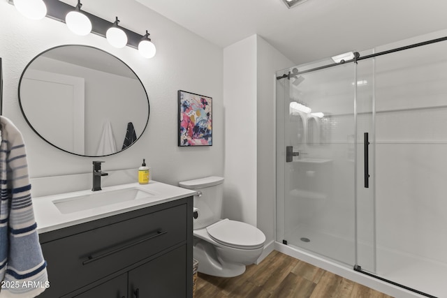 bathroom with vanity, hardwood / wood-style floors, an enclosed shower, and toilet