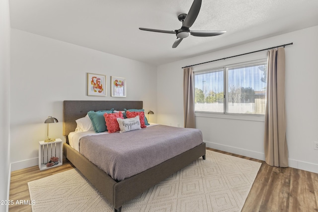 bedroom with hardwood / wood-style flooring, a textured ceiling, and ceiling fan