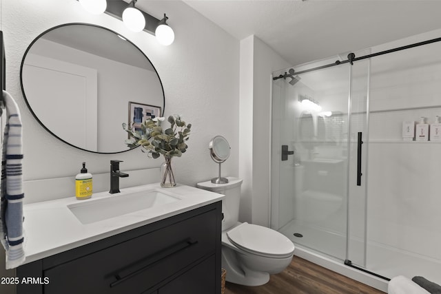 bathroom with hardwood / wood-style floors, vanity, toilet, and a shower with shower door