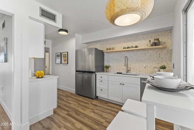 kitchen with sink, white cabinetry, stainless steel refrigerator, dark hardwood / wood-style flooring, and decorative backsplash