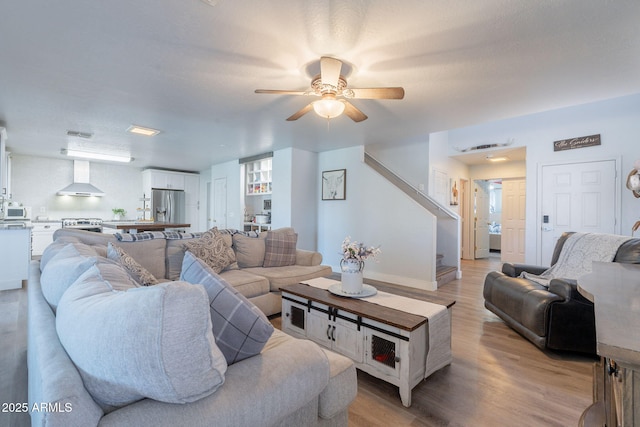 21188 N Duncan Dr, Maricopa, AZ 85138 - living room featuring stairway, a ceiling fan, light wood finished floors, and baseboards
