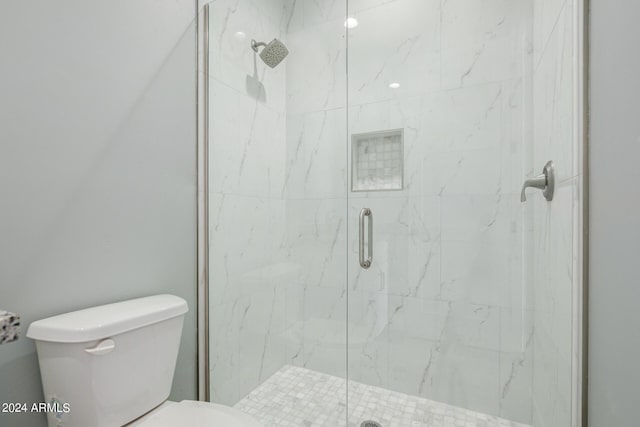 bathroom featuring toilet and a shower with door