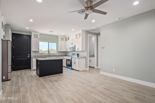 kitchen featuring white cabinetry, ceiling fan, stainless steel appliances, and a center island