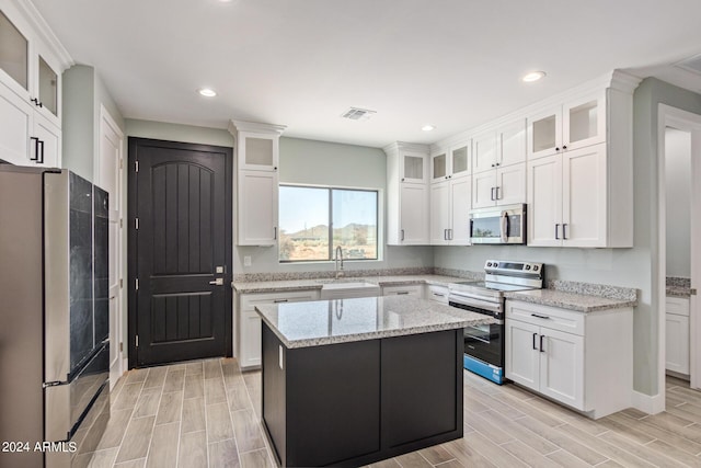 kitchen featuring stainless steel appliances, a center island, and white cabinets