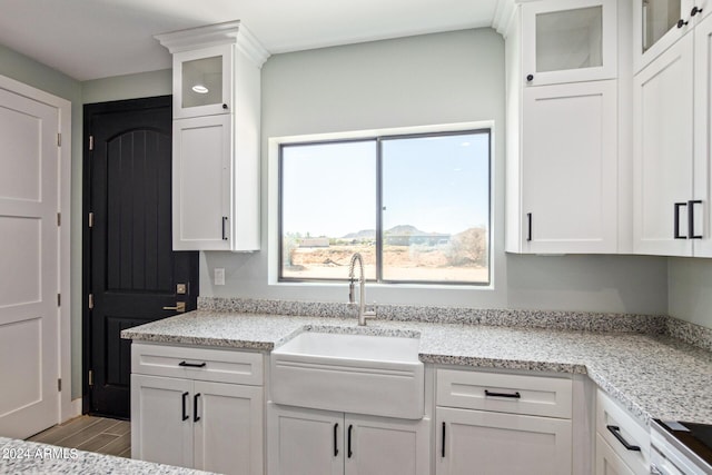 kitchen with white cabinetry, sink, light stone counters, and light hardwood / wood-style floors