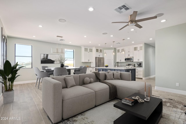 living room with ceiling fan and light hardwood / wood-style flooring